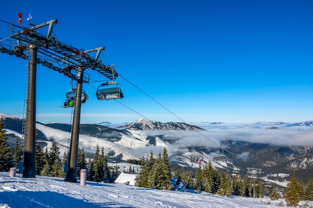 Stazione sciistica slovacca Jasna. Cielo azzurro e leggera nebbia tra le cime delle montagne. La neve brilla al sole. Seggiovia