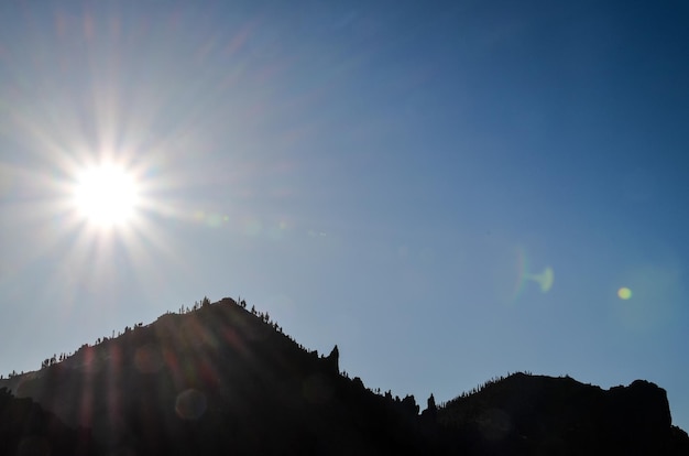 Stella del sole su un cielo blu sopra una siluetta della montagna