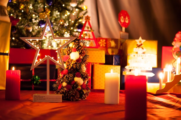 Stella di Natale davanti all'albero di Natale con ghirlande e decorazioni in casa. Albero verde decorativo e festoso