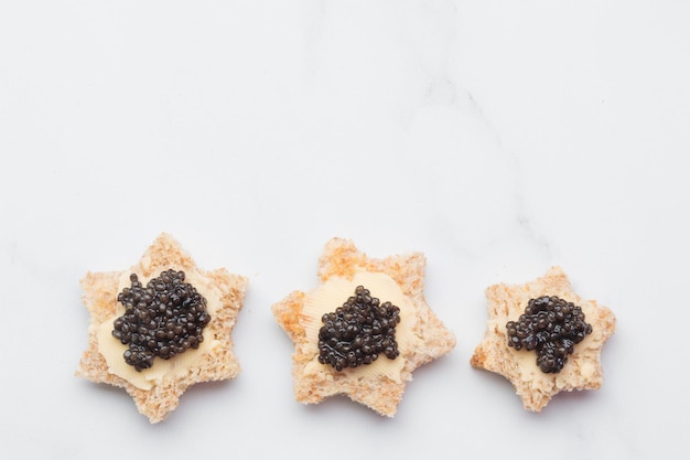 Stella di pane di antipasti di caviale nero su sfondo bianco vista dall'alto