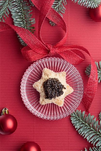 Stella di pane di antipasti di caviale nero su sfondo rosso decorato di Natale