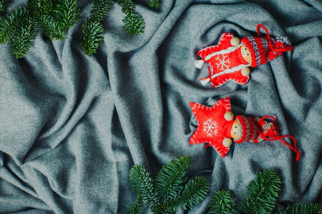 Stelle di natale lavorate a maglia rosse in cappelli divertenti. Bambole di Natale con rami di abete naturale sulla materia grigia.