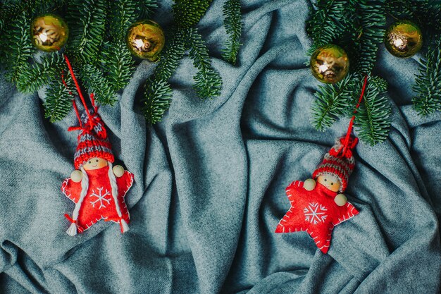 Stelle di natale lavorate a maglia rosse in cappelli divertenti. Bambole di Natale con rami di abete naturale sulla materia grigia.