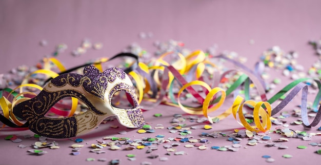 Stelle filanti e coriandoli della maschera di carnevale su sfondo rosa