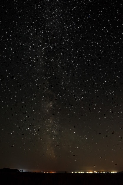 Stelle luminose nel cielo notturno sopra la città con illuminazione stradale