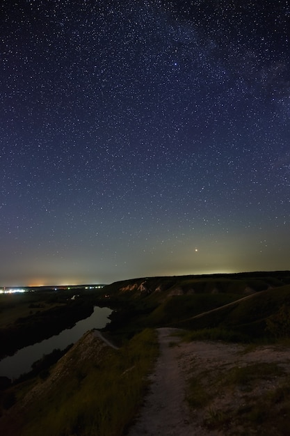 Stelle nel cielo notturno sopra la valle del fiume e la città