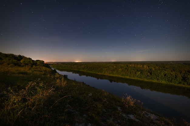 Stelle nel cielo notturno sul fiume. Illuminato dal chiaro di luna. Fotografato con una lunga esposizione.