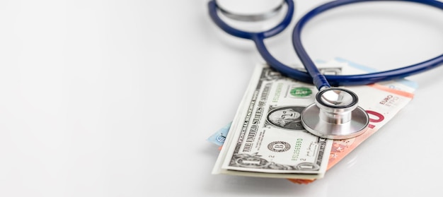 Stetoscopio adagiato su varie banconote in euro e negli Stati Uniti Concetto di educazione sanitaria per la ricchezza dell'assicurazione dei costi medici