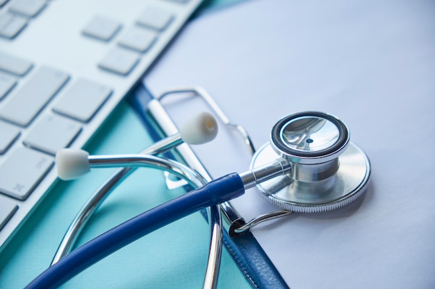 Stetoscopio con appunti e computer portatile sulla scrivaniaMedico che lavora in ospedale scrivendo una prescrizione Risultati dei test di concetto medico e sanitario nel fuoco selettivo di sfondo