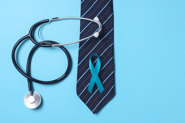 Stetoscopio cravatta e nastro blu simbolo della consapevolezza del cancro alla prostata isolato su sfondo blu