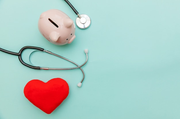 Stetoscopio dell'attrezzatura di medico della medicina o porcellino salvadanaio del phonendoscope e cuore rosso isolati su fondo blu pastello d'avanguardia