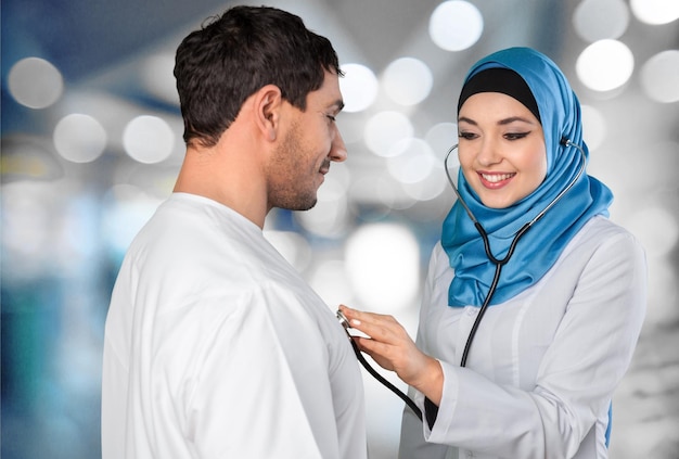 Stetoscopio femminile arabo musulmano della tenuta del medico con un paziente
