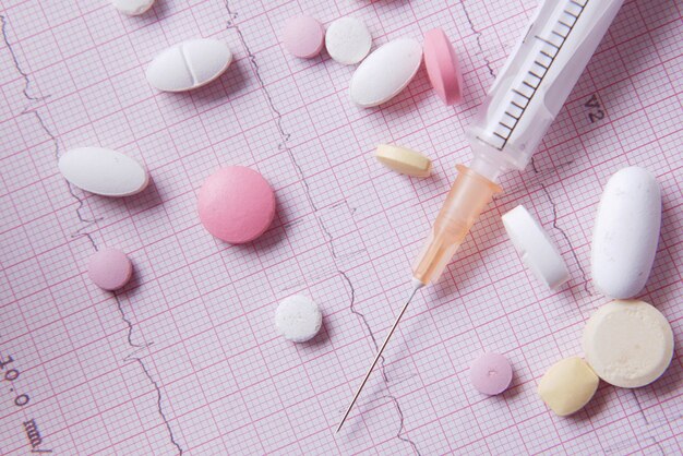 Stetoscopio pillola medica e siringa su un diagramma cardio