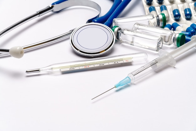 stetoscopio, termometro, siringa e capsule su sfondo grigio chiaro o bianco - vista dall'alto