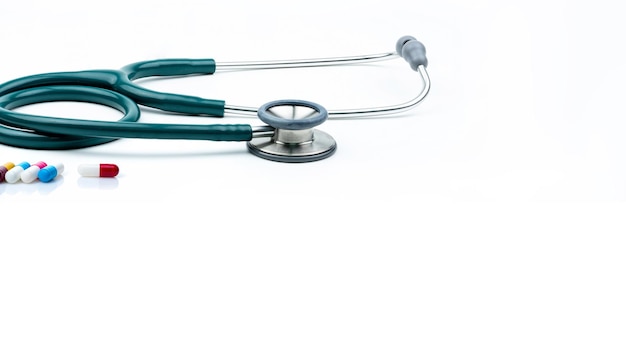 Stetoscopio verde e capsule in pillole su sfondo bianco Controllo sanitario Attrezzature per il medico cardiologico