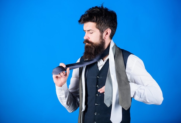 Stile classico Come abbinare la cravatta con la camicia e l'abito Uomo hipster con la barba tiene poche cravatte su sfondo blu Ragazzo con la barba che sceglie la cravatta Guida per gentiluomini Come scegliere la cravatta giusta
