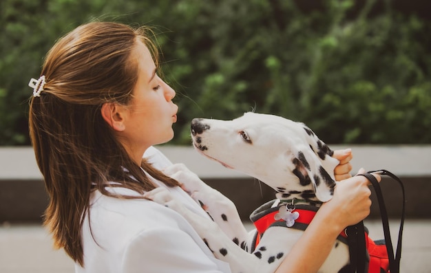 Stile di moda donna bella ragazza che cammina con il cane per strada cane leccare e baciare la ragazza