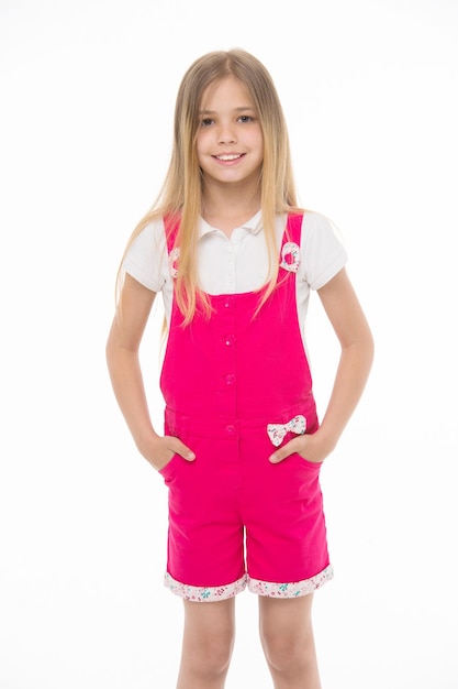 Stile di moda e tendenza Piccola ragazza sorridente in tuta rosa isolata su bianco Bambino sorridente con lunghi capelli biondi Modello bambino in tuta alla moda Infanzia felice e assistenza all'infanzia