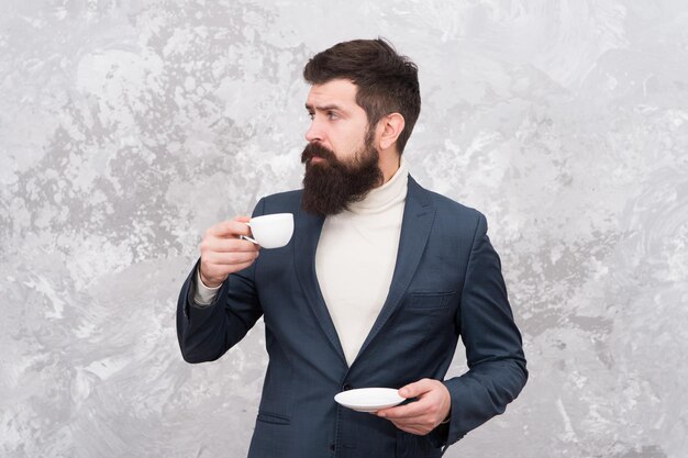 Stile di moda per uomini d'affari Abiti in stile casual intelligente per la vita in ufficio Miglior caffè servito per lui Caffè speciale Uomo bello uomo d'affari barbuto tenere una tazza di caffè Concetto di pausa caffè