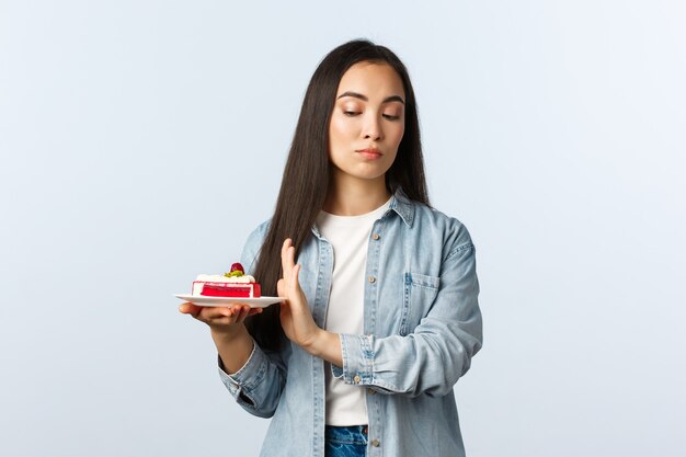 Stile di vita a distanza sociale, pandemia di covid-19, celebrazione delle vacanze durante il concetto di coronavirus. Ragazza asiatica arrogante riluttante che si prende cura del corpo, rifiuta il dessert, non vuole mangiare la torta di compleanno.