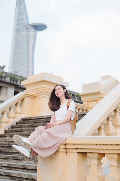 Stile di vita all'aperto primo piano ritratto di giovane donna felice in abito casual elegante seduto sul ponte sulla strada. Ragazza graziosa hipster divertirsi e godersi le vacanze.