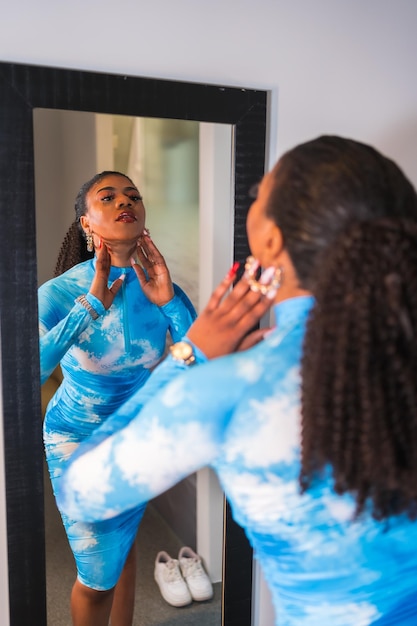 Stile di vita alla moda di una ragazza etnica nera con i capelli raccolti e un vestito blu