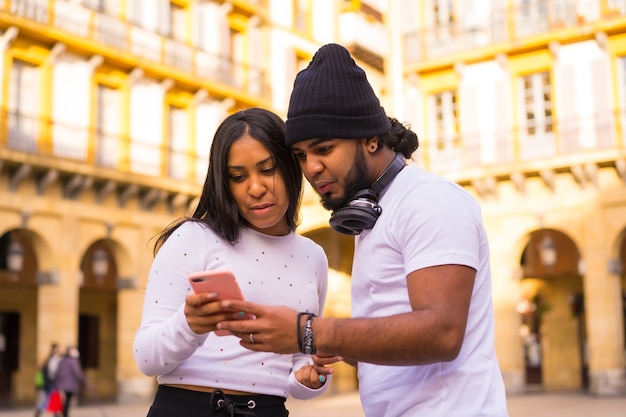 Stile di vita, amici neri latini che guardano i social media per strada