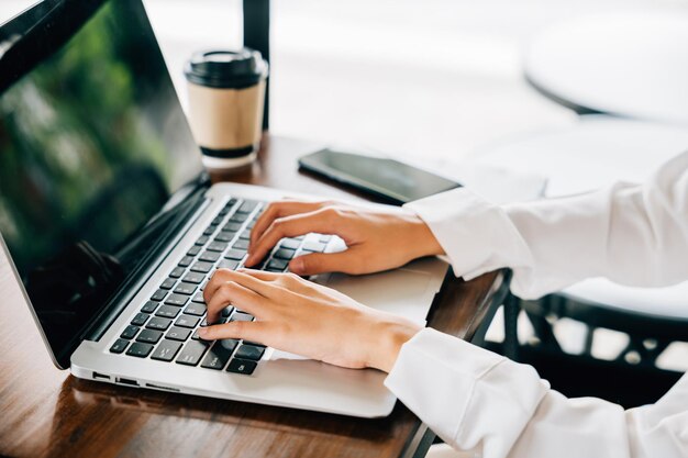 Stile di vita asiatico della giovane donna di affari che utilizza il computer portatile alla caffetteria del caffè