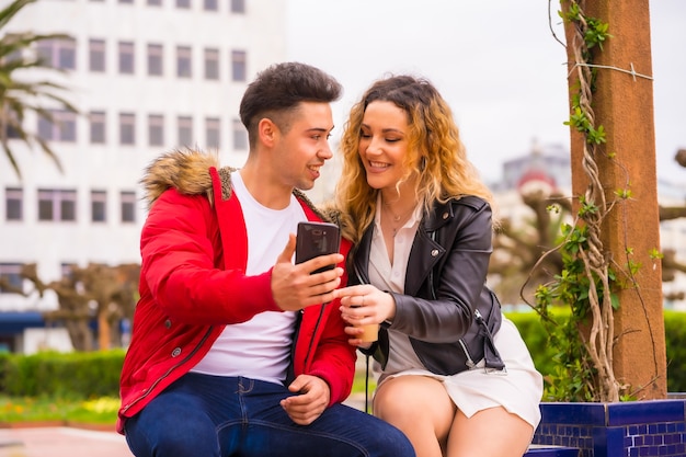 Stile di vita di una coppia caucasica che fa turismo di vacanza, in un parco cittadino guardando le cose su Internet con il cellulare