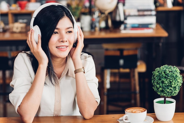 Stile di vita donna freelance che usa gli auricolari ascoltando musica durante il lavoro sul computer portatile nella caffetteria