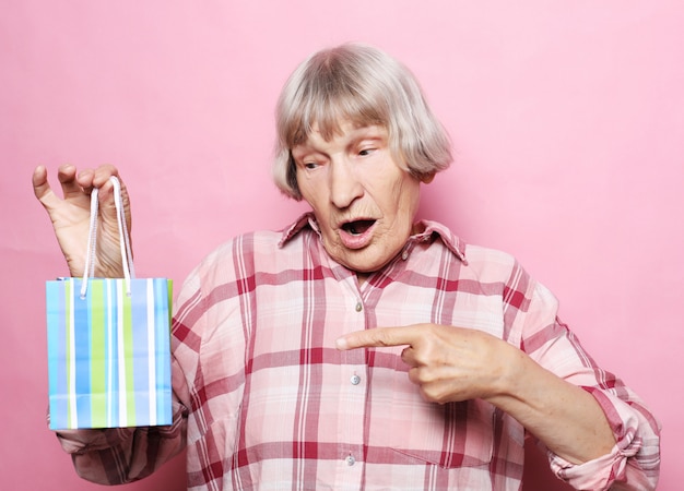 Stile di vita e concetto della gente della donna senior felice con il sacchetto della spesa sopra il rosa
