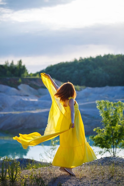 Stile di vita estivo di splendida donna felice che corre nella natura. In un lungo vestito giallo. Atmosfera romantica. Godendo il sole. Giorno soleggiato. Messa a fuoco selettiva