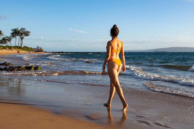 Stile di vita estivo donna abbastanza giovane con corpo sexy abbronzato Godersi la vita nell'acqua di mare limpida sulla spiaggia dell'isola tropicale