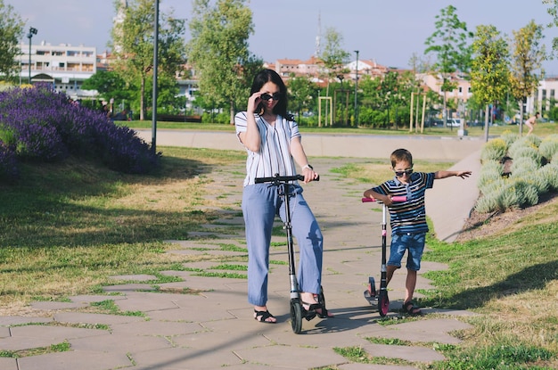 Stile di vita familiare felice madre ragazzo ragazza che cammina in città in scooter ridendo del divertimento estivo