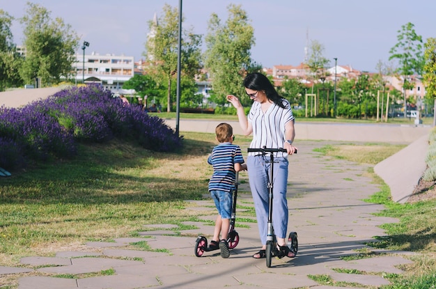 Stile di vita familiare felice madre ragazzo ragazza che cammina in città in scooter ridendo del divertimento estivo