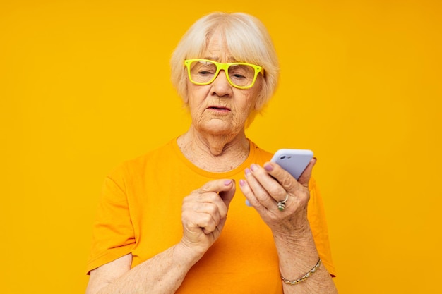 Stile di vita felice donna anziana in magliette gialle con sfondo giallo telefono