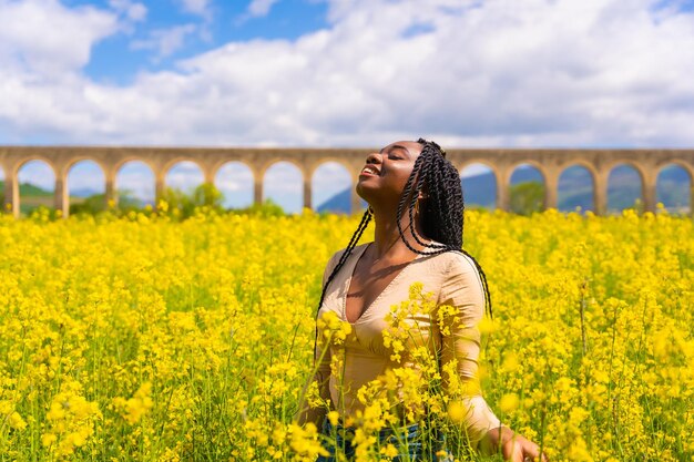 Stile di vita natura in libertà Ritratto di una ragazza di etnia nera con trecce in un campo di fiori gialli