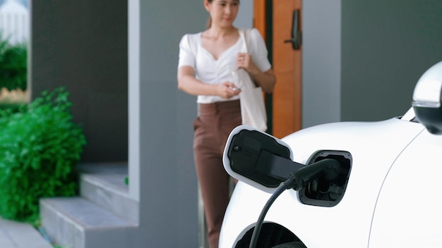 Stile di vita progressista di una donna con auto elettrica e stazione di ricarica domestica.