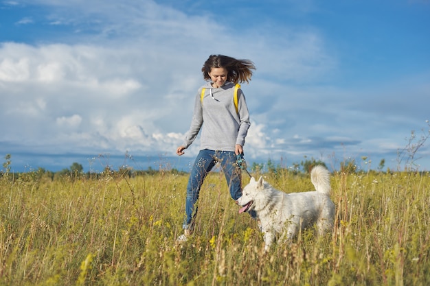 Stile di vita sano attivo, ragazza teenager che funziona con il cane husky bianco