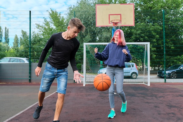 Stile di vita sano e attivo della gioventù, hobby e tempo libero, ragazzi e ragazze su un campo da basket all'aperto che giocano a basket di strada