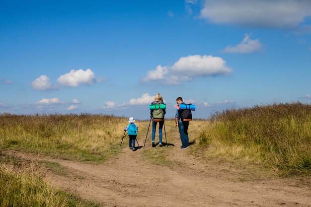 Stile di vita sano, escursioni in famiglia in montagna con zaini e bastoni da passeggio