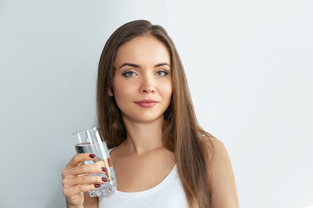 Stile di vita sano Giovane donna che beve da un bicchiere di acqua fresca. Assistenza sanitaria. Bevande. Ritratto del modello femminile sorridente felice che tiene vetro trasparente.