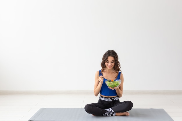 Stile di vita sano, persone e concetto di sport - Yoga donna con una ciotola di insalata di verdure dopo