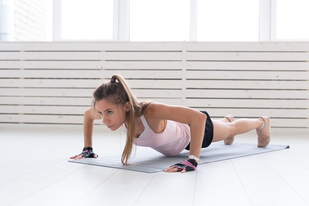 Stile di vita sano, sport, concetto di persone: una giovane donna sta facendo fitness in palestra oa casa. Sta premendo nella tuta sportiva.