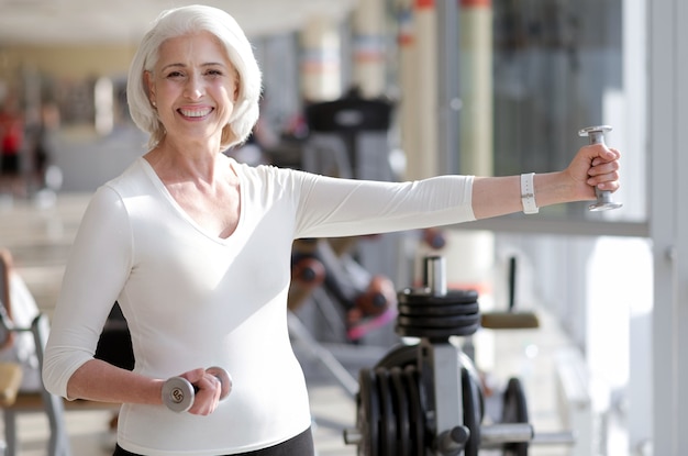 Stile di vita sportivo. Montare la donna senior sorridente e mantenersi in buona salute esercitandosi in palestra.