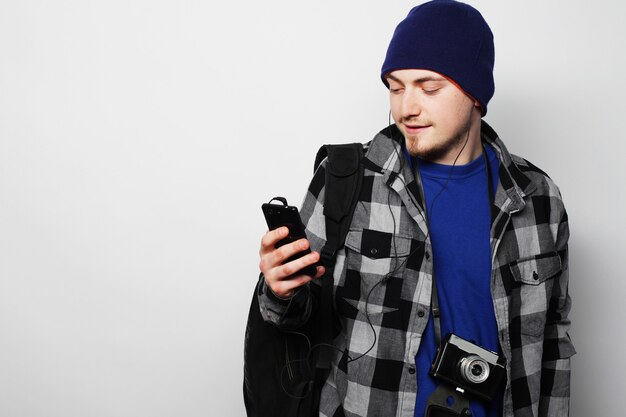 Stile di vita, tecnologia e concetto di persone: uomo allegro in camicia e cappello che utilizza smartphone su sfondo grigio