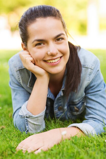 stile di vita, vacanze estive, tempo libero e concetto di persone - ragazza sorridente sdraiata sull'erba nel parco