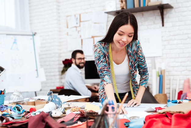 Stilista della donna che disegna con il righello su carta