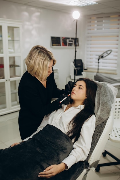 Stilista di bellezza che fa modellare le labbra prima della procedura di trucco permanente presso il salone di bellezza