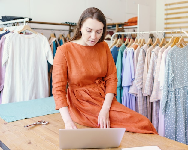 Stilista di moda femminile che crea design di abbigliamento online su laptop